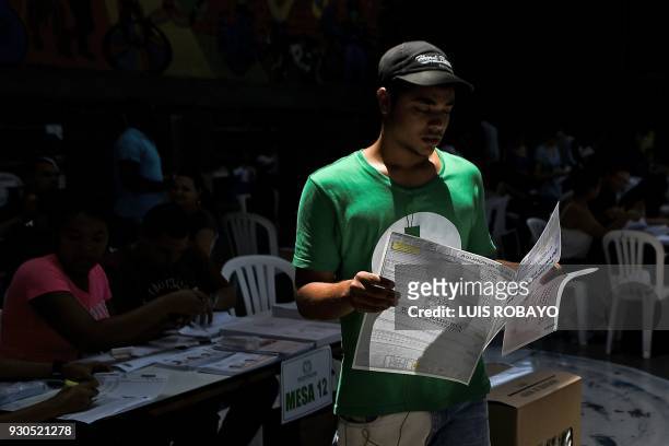Man reads an electoral sheet at a polling station in Cali, Valle del Cauca Department, during parliamentary elections in Colombia on March 11, 2018....