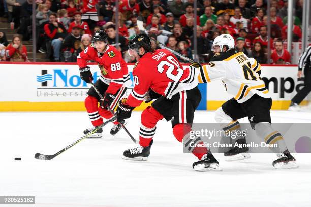 Brandon Saad of the Chicago Blackhawks and Torey Krug of the Boston Bruins chase the puck in the second period at the United Center on March 11, 2018...