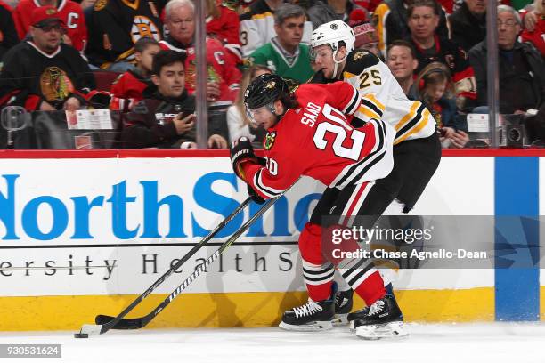 Brandon Saad of the Chicago Blackhawks and Brandon Carlo of the Boston Bruins chase the puck in the second period at the United Center on March 11,...