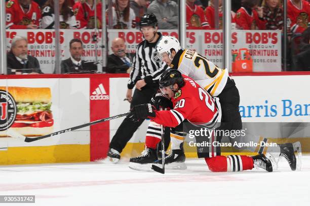 Brandon Saad of the Chicago Blackhawks and Brandon Carlo of the Boston Bruins chase the puck in the second period at the United Center on March 11,...