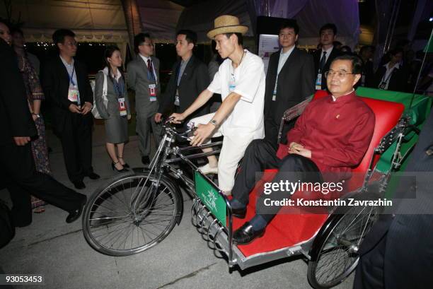 China's President Hu Jintao rides in a traditional trishaw to attend a dinner after the 'Singapore Evening' concert during the second day of the Asia...