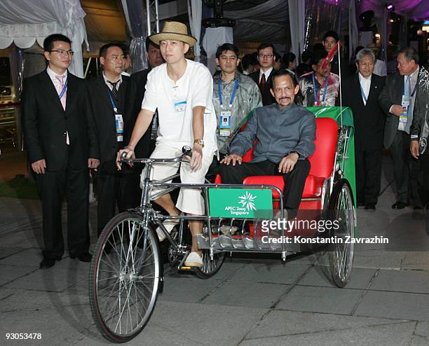 Brunei's Sultan Hassanal Bolkiah rides in a traditional trishaw to attend a dinner after the 'Singapore Evening' concert during the second day of the...