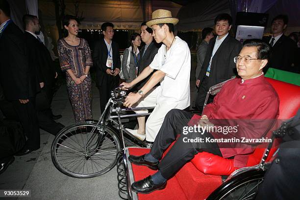 China's President Hu Jintao rides in a traditional trishaw to attend a dinner after the 'Singapore Evening' concert during the second day of the Asia...