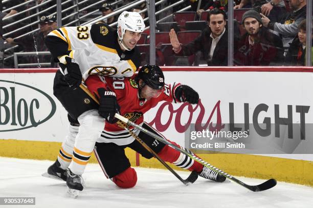 Zdeno Chara of the Boston Bruins hits Brandon Saad of the Chicago Blackhawks in the third period at the United Center on March 11, 2018 in Chicago,...