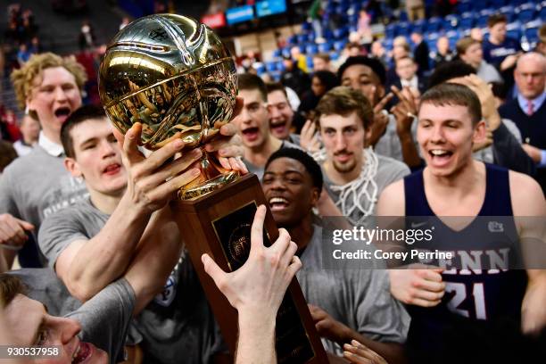 The Pennsylvania Quakers men's basketball team hold up the championship trophy after winning the Men's Ivy League Championship Tournament at The...