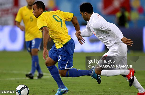 England's Joleon Lescott runs to intercept Brazil's Luis Fabiano as he advances with the ball during their friendly football match at the Khalifa...