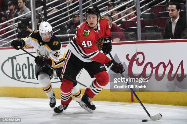 John Hayden of the Chicago Blackhawks approaches the puck ahead of Matt Grzelcyk of the Boston Bruins in the third period at the United Center on...