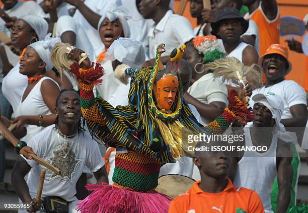 Ivorian supporters dance with traditional costums to celebrate their victory over Guinea during their World Cup and CAN 2010 football match on...