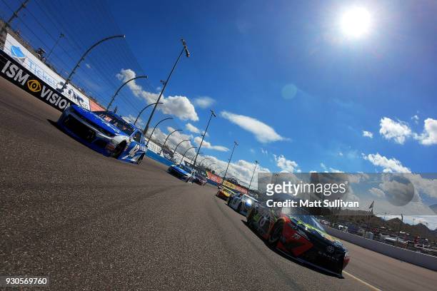 Martin Truex Jr., driver of the 5-hour Energy/Bass Pro Shops Toyota, and Kyle Larson, driver of the Credit One Bank Chevrolet, lead the field during...