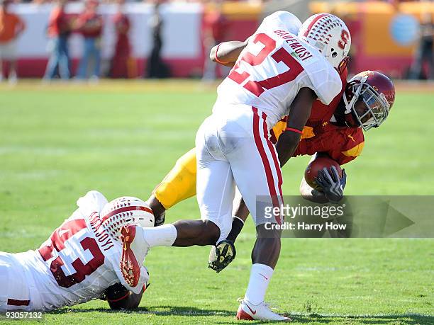 Joe McKnight of the USC Trojans is tackled by Johnson Bademosi and Chike Amajoyi of the Stanford Cardinal during the first half at the Los Angeles...