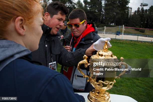 Blind person uses a white glove to feel the shape of the Webb Ellis Cup on display before the start of the match of Spain against Germany as part of...