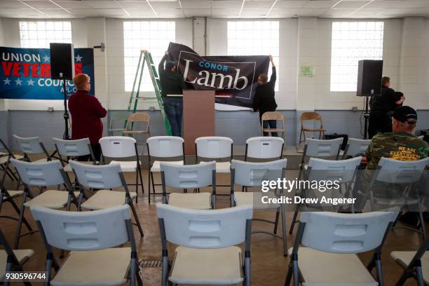 Volunteers hang a banner before the start of a rally for Conor Lamb, Democratic Congressional candidate for Pennsylvania's 18th district, at the...