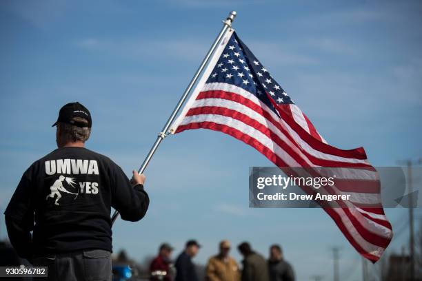 Union member holds an American flag before the start of a campaign rally with United Mine Workers of America at the Greene County Fairgrounds, March...