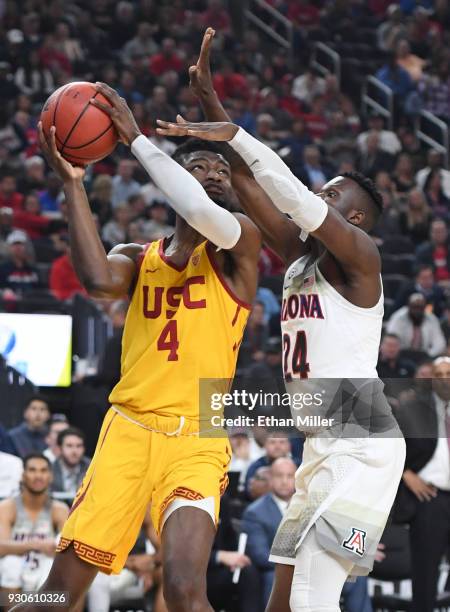 Chimezie Metu of the USC Trojans drives to the basket against Emmanuel Akot of the Arizona Wildcats during the championship game of the Pac-12...