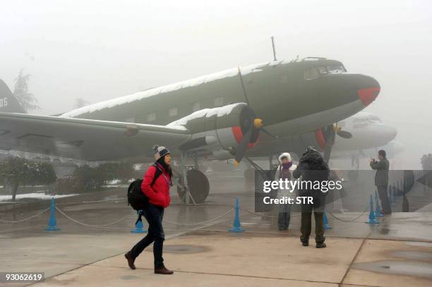 Visitors admire a millitary plane on display at an airforce museum to mark the 60th birthday of the Chinese People's Liberation Army air force in...