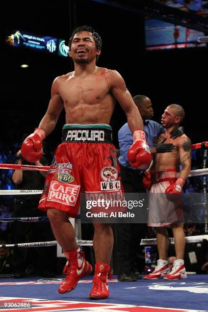 Manny Pacquiao celebrates his 12 round TKO victory against Miguel Cotto as Cotto is consoled by referee Kenny Bayless after their WBO welterweight...