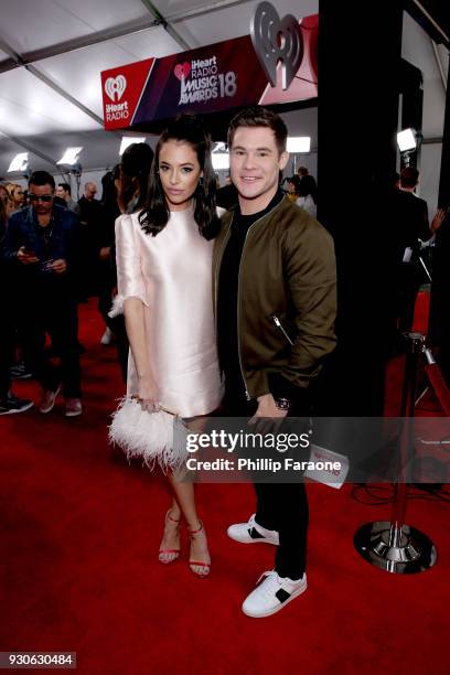 Chloe Bridges and Adam DeVine attend the 2018 iHeartRadio Music Awards which broadcasted live on TBS, TNT, and truTV at The Forum on March 11, 2018...