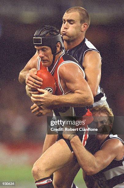 Nathan Burke for St Kilda is tackled by Steven King and Glenn Kilpatrick for Geelong, during the match between the St Kilda Saints and the Geelong...