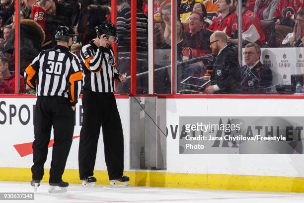 Referees Kendrick Nicholson and Mike Hasenfratz get ready to review a goal from a coach's challenge during a game between the Ottawa Senators and the...