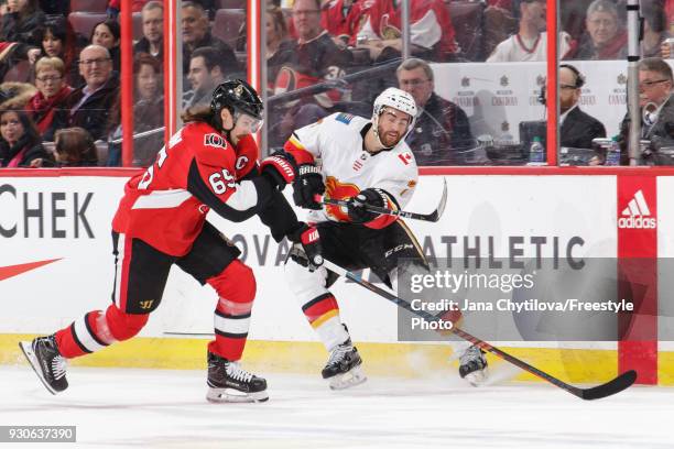 Brodie of the Calgary Flames gets rid of the puck as Erik Karlsson of the Ottawa Senators reacts at Canadian Tire Centre on March 9, 2018 in Ottawa,...