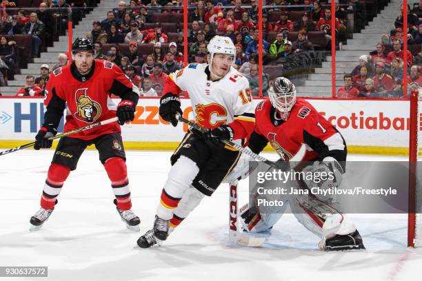 Teammates Mike Condon and Cody Ceci of the Ottawa Senators defend against Matthew Tkachuk of the Calgary Flames at Canadian Tire Centre on March 9,...