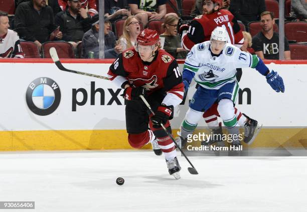 Christian Dvorak of the Arizona Coyotes advances the puck up ice ahead of Nikolay Goldobin of the Vancouver Canucks during the first period at Gila...