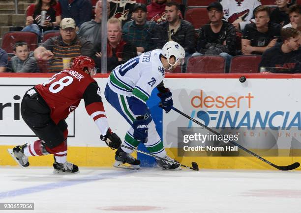 Brandon Sutter of the Vancouver Canucks and Jordan Martinook of the Arizona Coyotes skate for a loose puck along the boards during the first period...