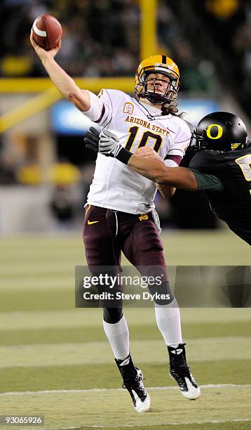 Quarterback Samson Szakacsy of the Arizona State Sun Devils throws a touchdown pass as linebacker Kenny Rowe of the Oregon Ducks applies pressure in...