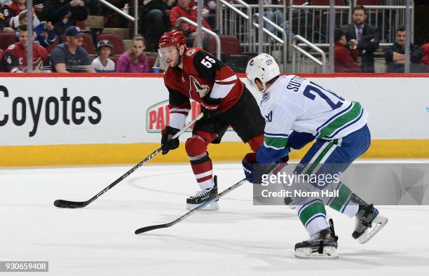 Jason Demers of the Arizona Coyotes skates with the puck as Brandon Sutter of the Vancouver Canucks defends during the first period at Gila River...