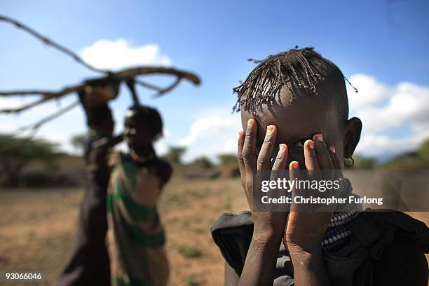 Girl from the remote Turkana tribe in Northern Kenya hides her face as she and her family collect wood for charcoal on November 9, 2009 near Lodwar,...