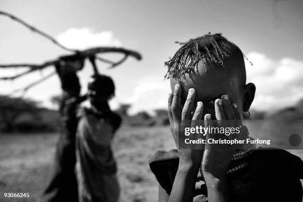 Girl from the remote Turkana tribe in Northern Kenya hides her face as she and her family collect wood for charcoal on November 9, 2009 near Lodwar,...