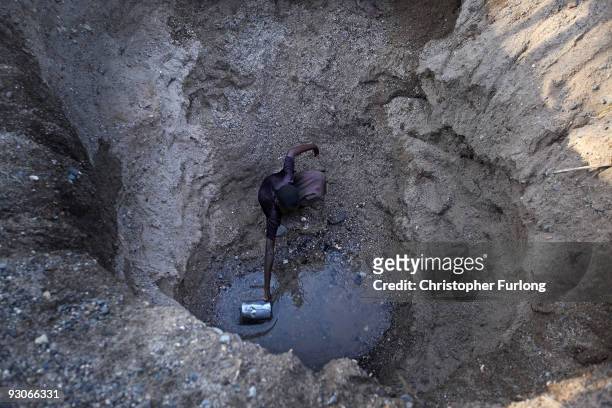 Children from the remote Turkana tribe in Northern Kenya dig a hole in a river bed to retrieve water. As water levels dwindle many children are...