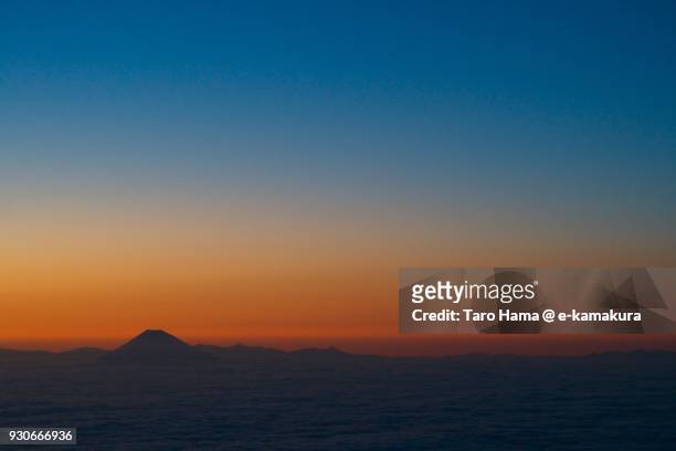 silhouette of mt. fuji in blue and orange-colored gradation sky in japan sunset time aerial view from airplane - gradation stock pictures, royalty-free photos & images