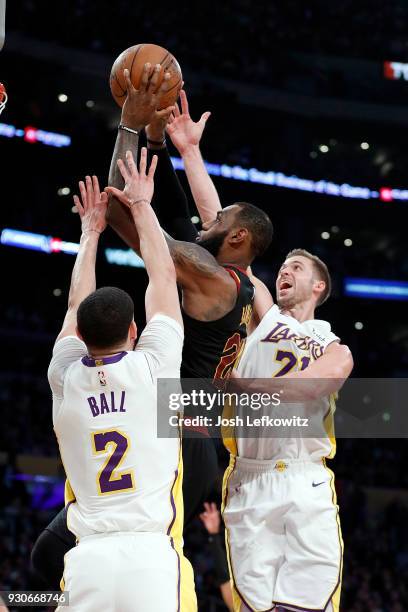 LeBron James of the Cleveland Cavaliers attempts a layup over Lonzo Ball and Travis Wear of the Los Angeles Lakers during the second quarter of the...