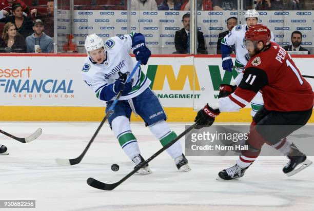 Troy Stecher of the Vancouver Canucks and Brendon Perlini of the Arizona Coyotes battle for control of the puck during the third period at Gila River...
