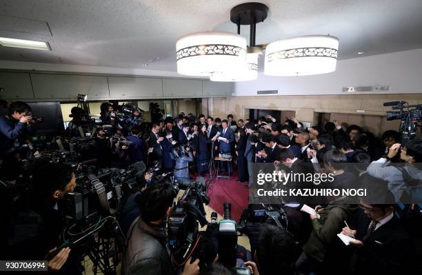 Japan's Finance Minister Taro Aso answers questions as he is surrounded by the media during a press briefing at the finance ministry in Tokyo on...