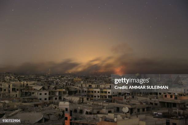 Lights and smoke are seen during Syrian government bombardment on the rebel-controlled town of Arbin, in the besieged Eastern Ghouta region on the...