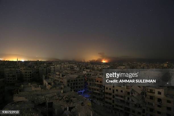Lights and smoke are seen during Syrian government bombardment on the rebel-controlled town of Arbin, in the besieged Eastern Ghouta region on the...