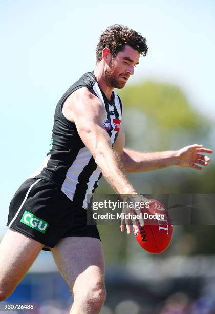 Tyson Goldsack of the Magpies and Marcus Adams of the Bulldogs compete for the ball kicks the ball during the JLT Community Series AFL match between...