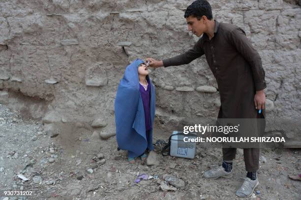 An Afghan health worker administers the polio vaccine to a child during a vaccination campaign on the outskirts of Jalalabad on March 12, 2018....