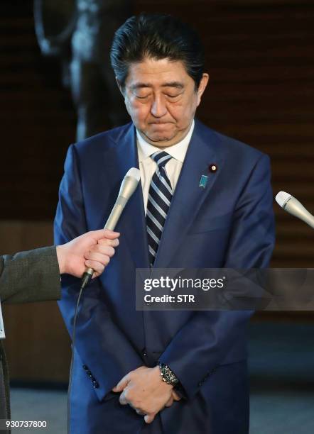 Japan's Prime Minister Shinzo Abe apologizes during a press briefing at his office in Tokyo on March 12, 2018. - Finance Minister Taro Aso admitted...