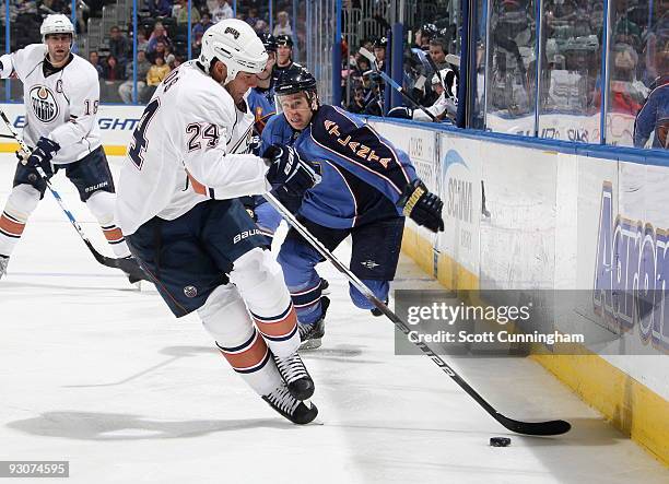 Steve Staios of the Edmonton Oilers collects the puck against Todd White of the Atlanta Thrashers at Philips Arena on November 15, 2009 in Atlanta,...