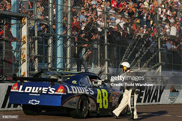 Jimmie Johnson, driver of the Lowe's Chevrolet, takes the checkered flag from a NASCAR official after winning the NASCAR Sprint Cup Series Checker...