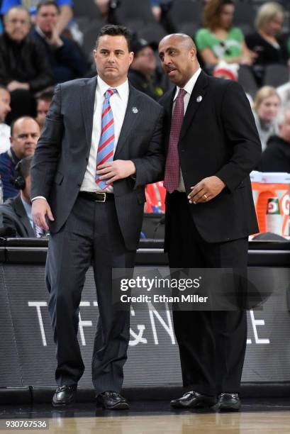 Head coach Sean Miller and associate head coach Lorenzo Romar of the Arizona Wildcats talk during a quarterfinal game of the Pac-12 basketball...