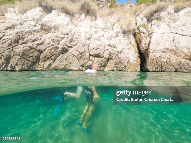 father and son snorkeling in greece - half underwater foto e immagini stock
