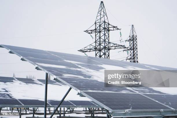 An electricity pylon carrying high voltage power cables stands near snow covered solar panels in the solar park operated by Solar Chernobyl in...