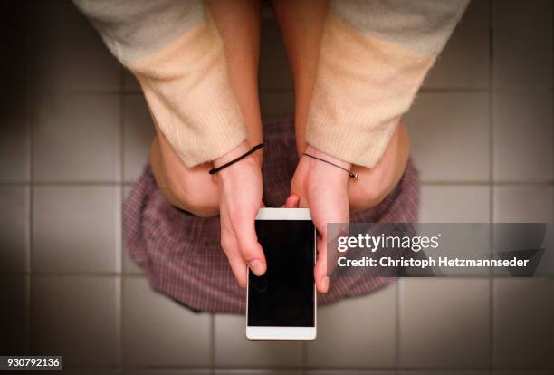 using smartphone on toilet - woman in bathroom stockfoto's en -beelden