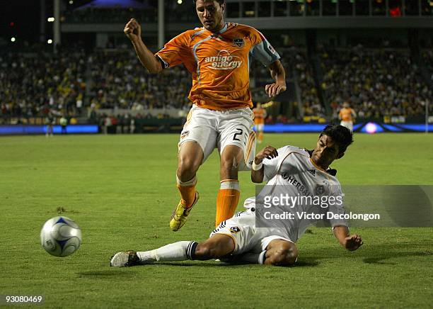 DeLagarza of the Los Angeles Galaxy slides in to clear the ball away from Brian Ching of the Houston Dynamo during the MLS Western Conference...