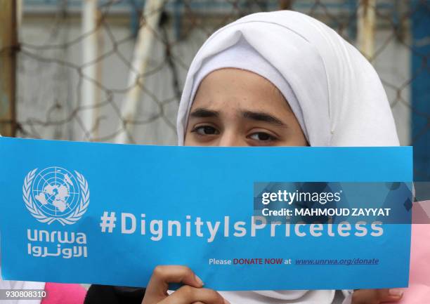 Palestinian refugee holds a placard at a school belonging to the United Nations Relief and Works Agency for Palestinian Refugees in the town of...