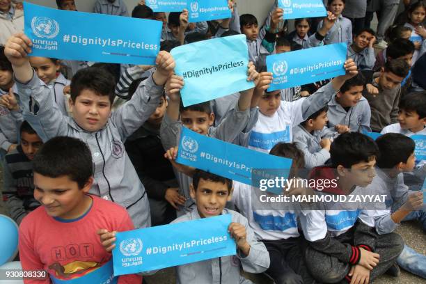 Palestinian refugees hold placards at a school belonging to the United Nations Relief and Works Agency for Palestinian Refugees in the town of...